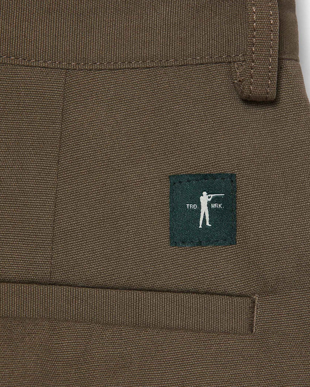 Close-up of brown pants with a small logo on a white background