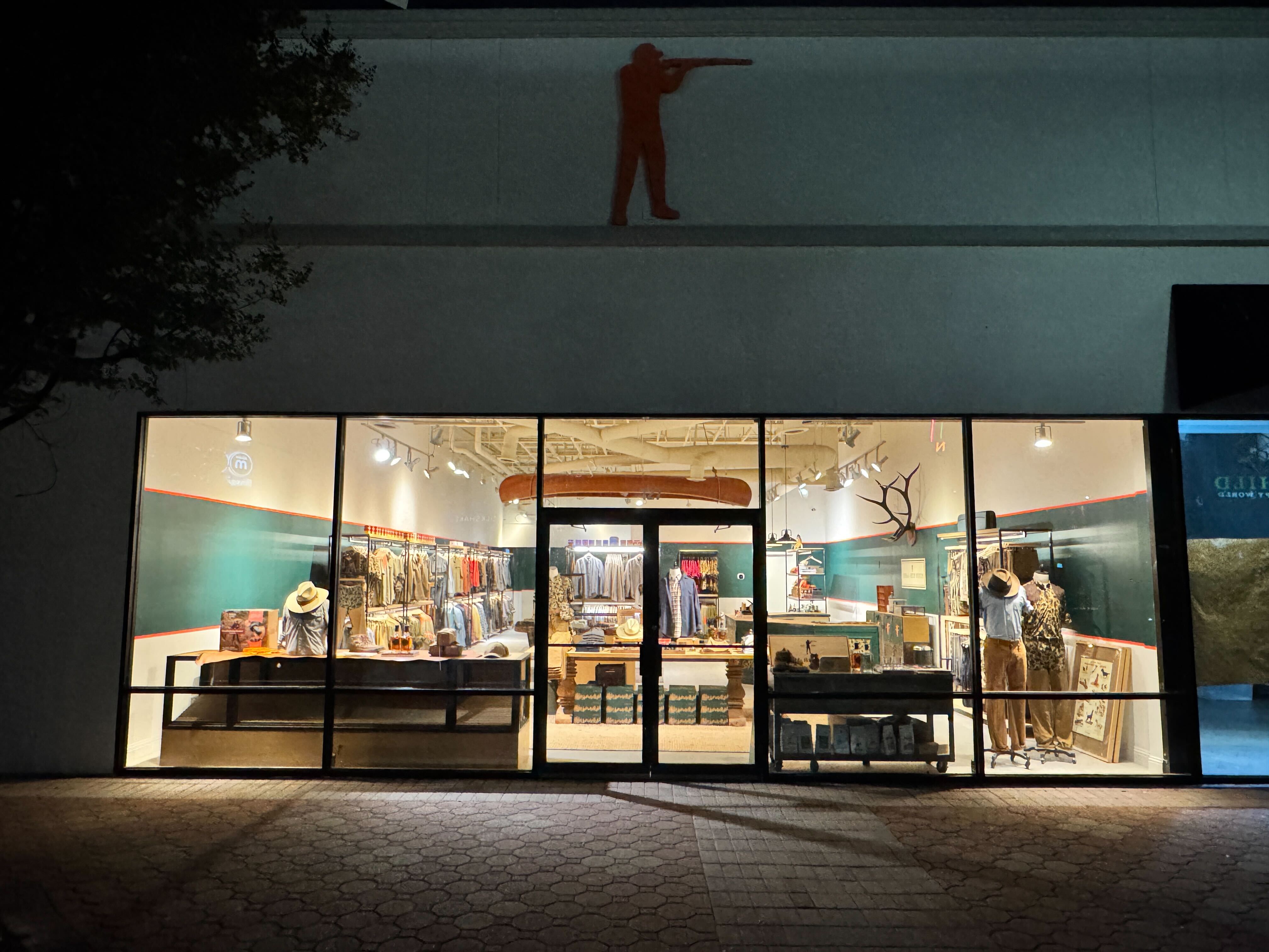Storefront with glass windows displaying various items, illuminated by interior lights.